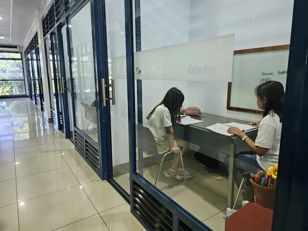 マンツーマンクラスが並ぶ廊下とその一室で授業を行っている講師と学生