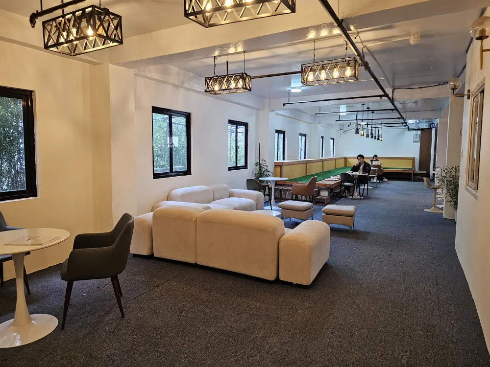 ソファーやテーブル席などが並ぶ奥行きのある学習ラウンジで自習をする2人の学生