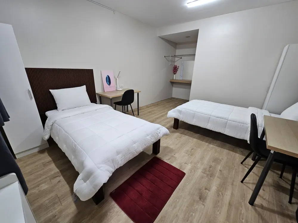 2台のベッドと机が配置されたA&J ECO Campusのデラックスツインルームの室内全景