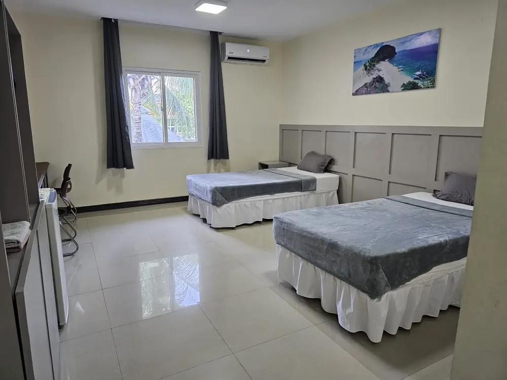 シングルベッド2台、冷蔵庫、勉強机、ワードローブ、エアコンが設置されたツインルーム
