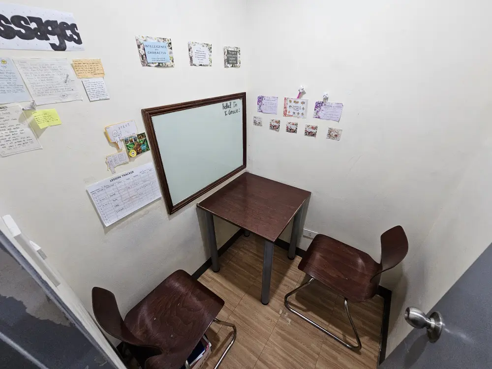 勉強机、ガラス製ホワイトボード、椅子2脚がL字に配置されたCIJのマンツーマン教室