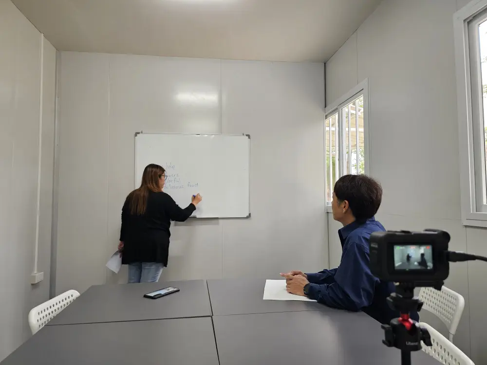 体験授業でホワイトボードに書き込むA&Jの講師と説明に聞き入るGrit留学の代表