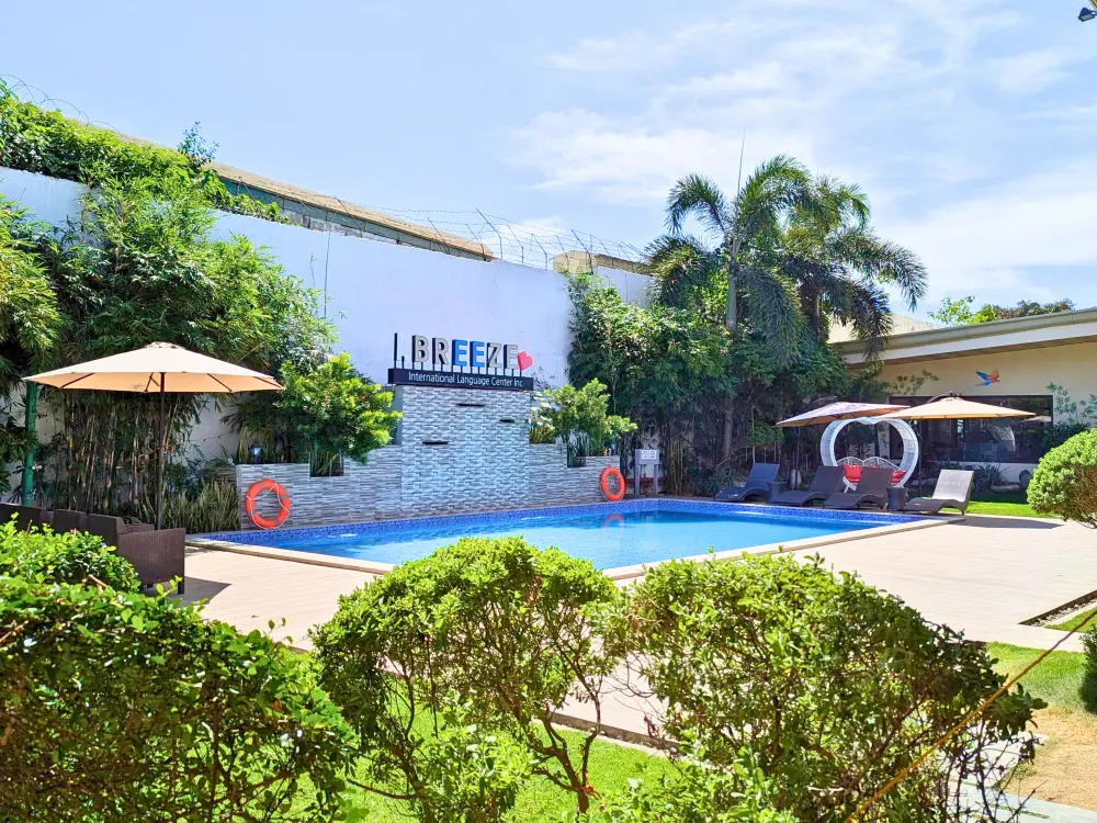 I.Breezeの敷地内にある庭に囲まれたスイミングプールとパラソル
