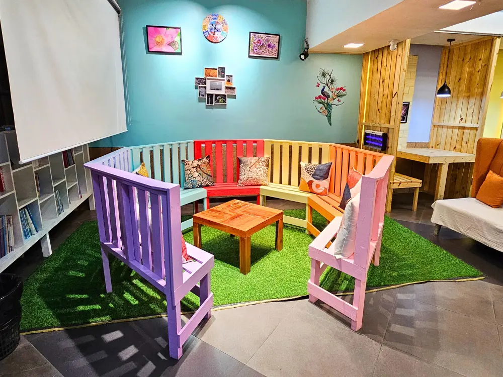 WALESのスチューデントラウンジに円形に配置された7色の木製椅子と小さなテーブル