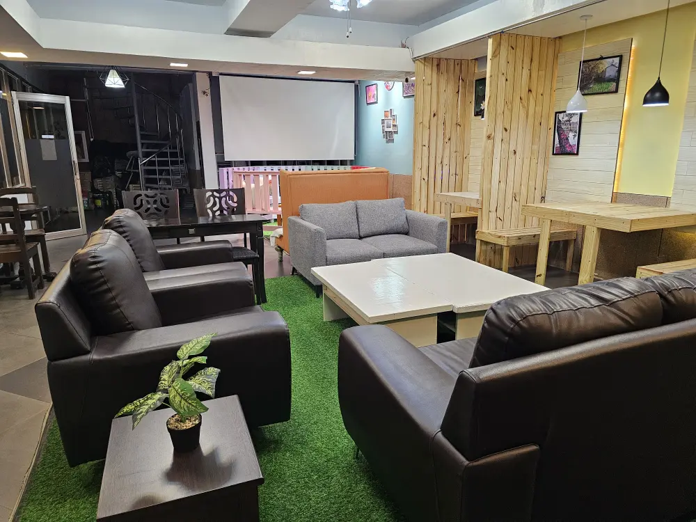 白いテーブルとコの字に配置された黒とグレーの大きなソファーがある学生ラウンジ