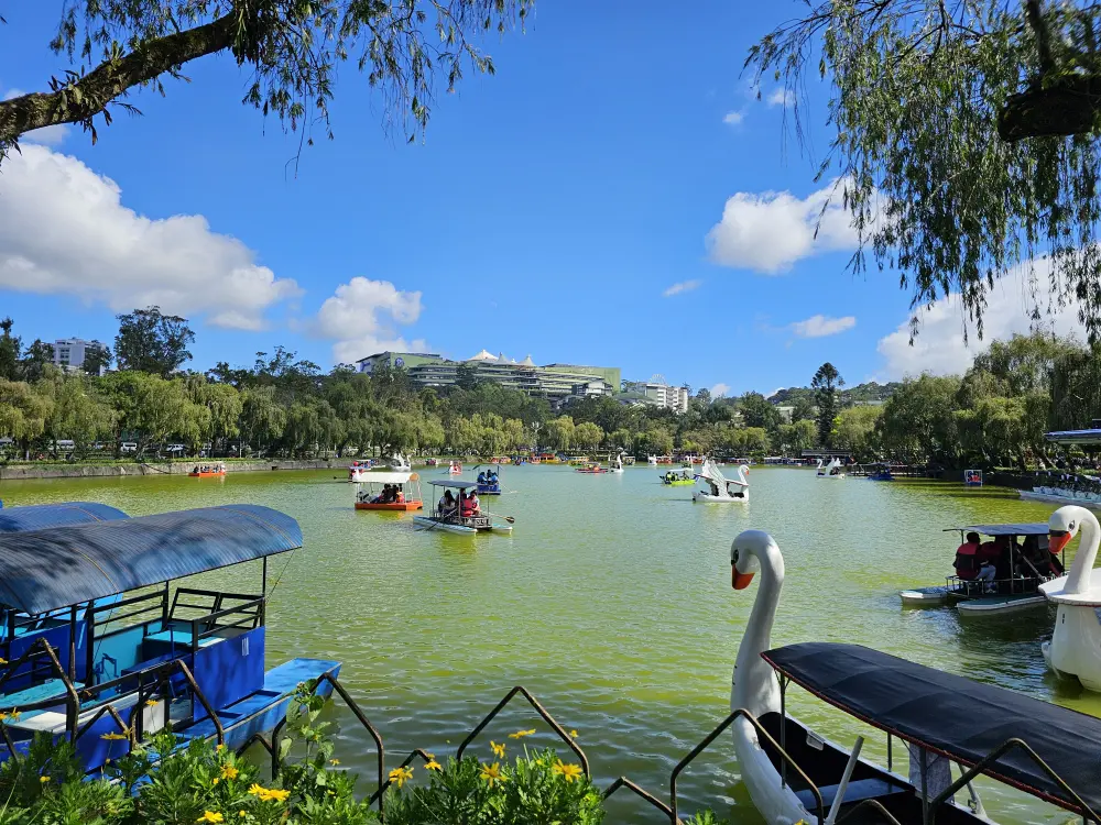 バギオのバーナム・パークにある湖でボートを楽しむ人々と高台にあるSMモール