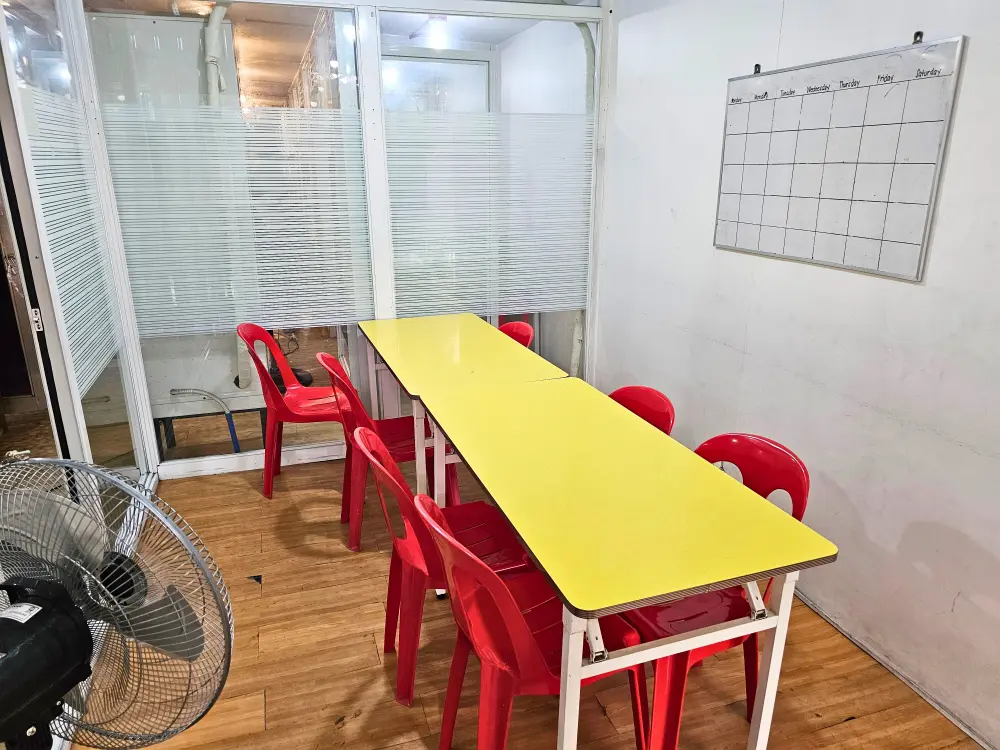 部屋の中央に黄色いテーブルと赤い椅子が並んだJICチャレンジャーのグループクラス用教室
