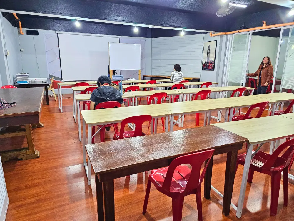 JIC Challenger Campusのイーストフィールド校舎にあるファンクションホールの椅子に座る2人の学生