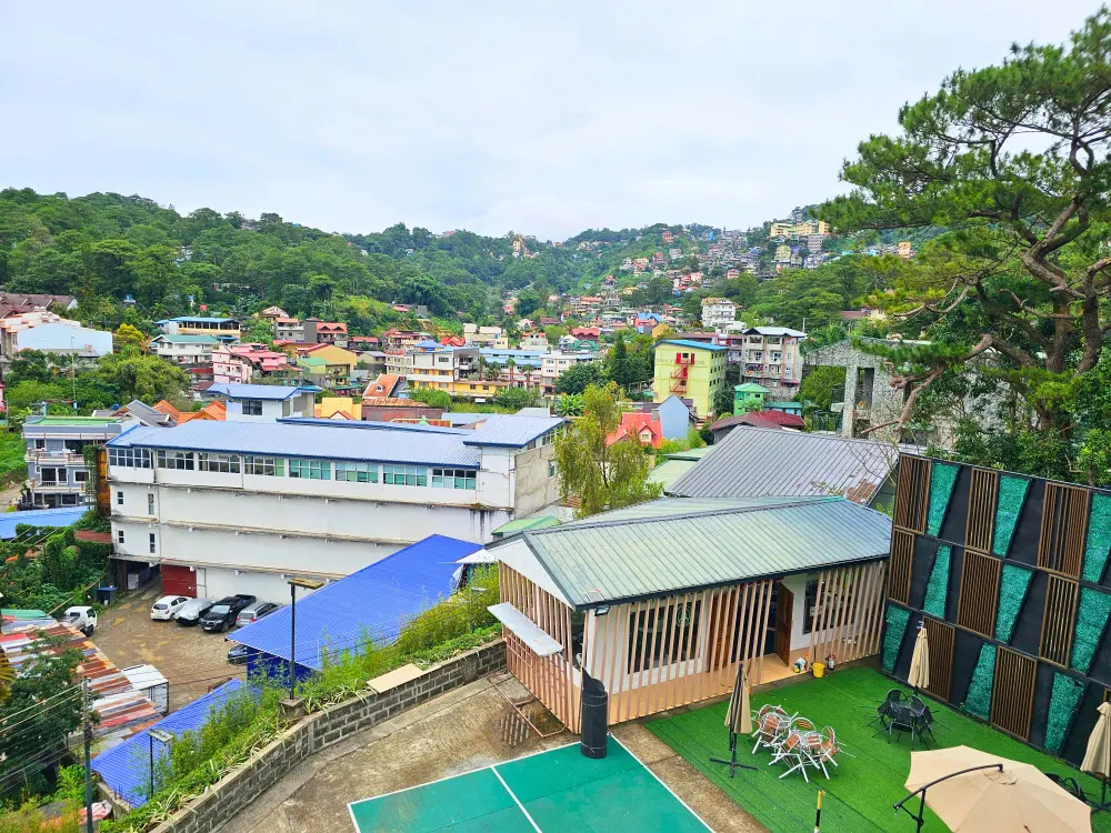 JICチャレンジャーのEast Field校舎から見た屋外テーブル席やジムのある校庭と周囲の街並み