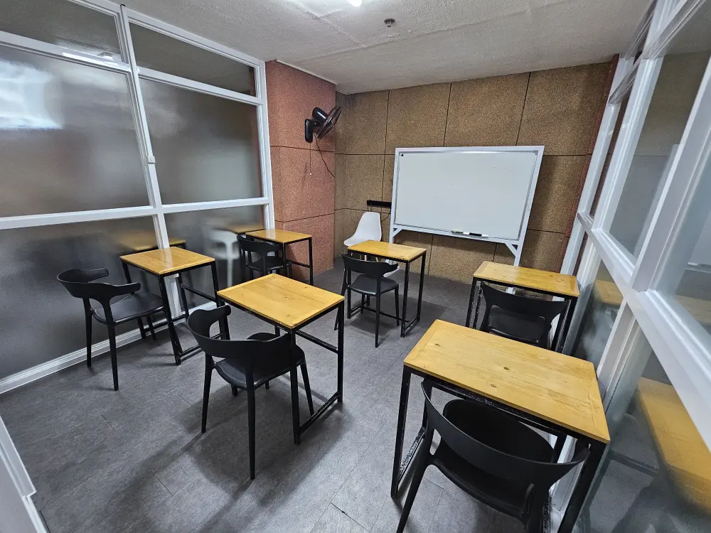 6組の机と椅子が配置され、大きなホワイトボードがあるWALESのグループクラス用教室