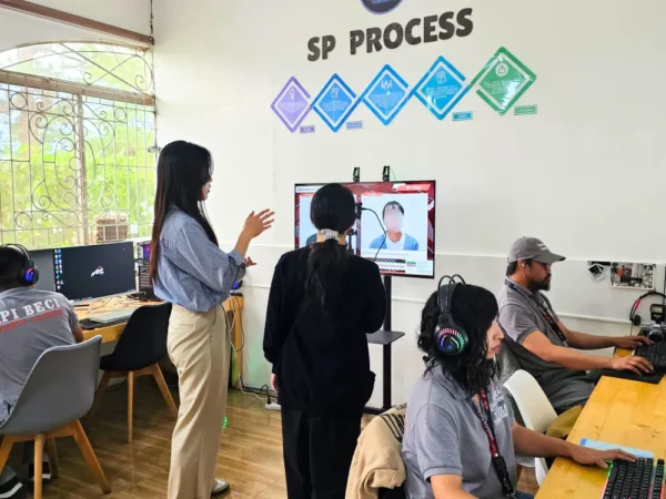 PCに向かいSPテストの書き起こしを行う講師と、SPプログラムの説明をしている韓国人マネージャー