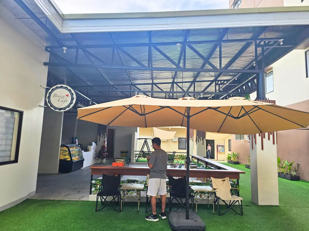 PrimeキャンパスにあるBreeze Caféのパラソルの下に立つアイブリーズの学生