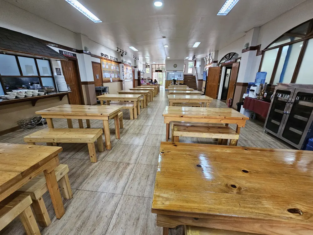 BECI Spartaキャンパスのダイニングホールに整然と並ぶ木製テーブルとベンチ