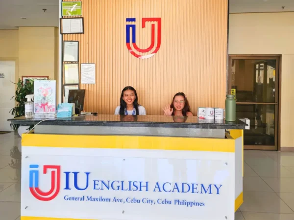 IU English Academyのフロントデスクに座る笑顔のフィリピン人スタッフ2名