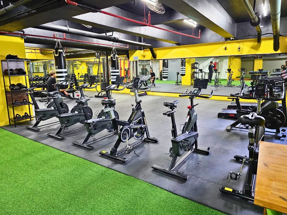 スピンバイクやトレッドミルが並び、壁一面に大型ミラーが設置されたIU English Academyのフィットネスジム