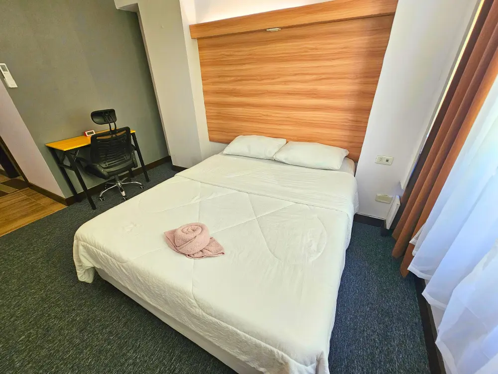 白い寝具のキングベッドに、綺麗に巻かれたピンク色のバスタオルが置かれたIU Englishのシングルルーム