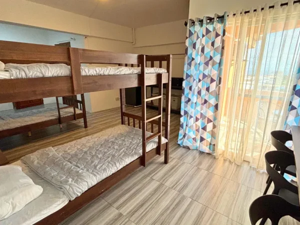 2段ベッドと勉強机が配置されたGenius Englishのバルコニー付き4人部屋