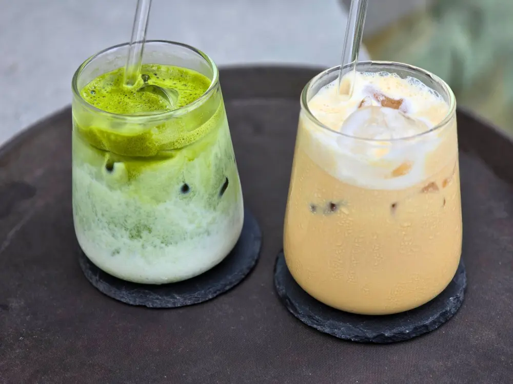 黒い石製のコースターにのった、緑色のアイス抹茶ラテと淡いオレンジ色のAngelotini