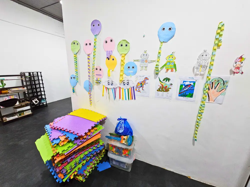 カラフルなマットやおもちゃが置かれ、子どもの作品が飾られたキッズルーム