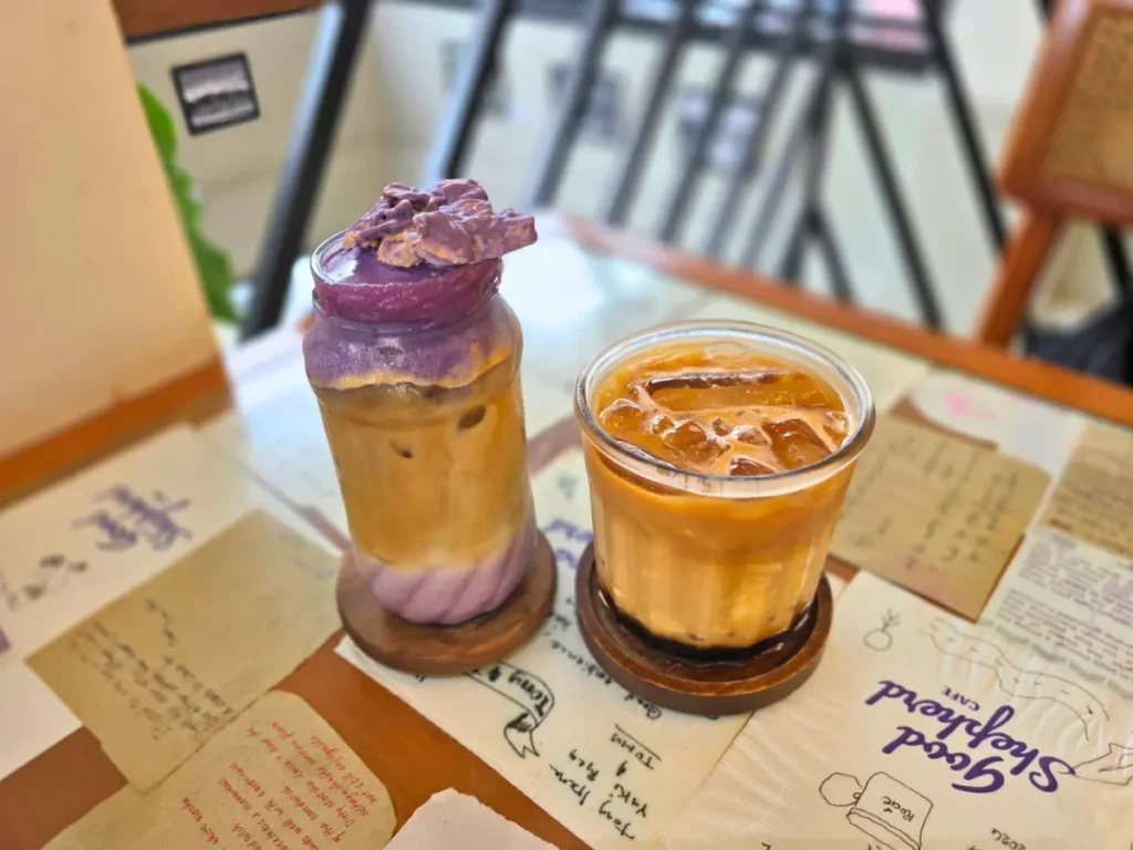 フィリピン・バギオにあるGood Shepherd Caféのテーブルに並ぶ、木製コースターに置かれたShepherd’s LatteとTaho Latte