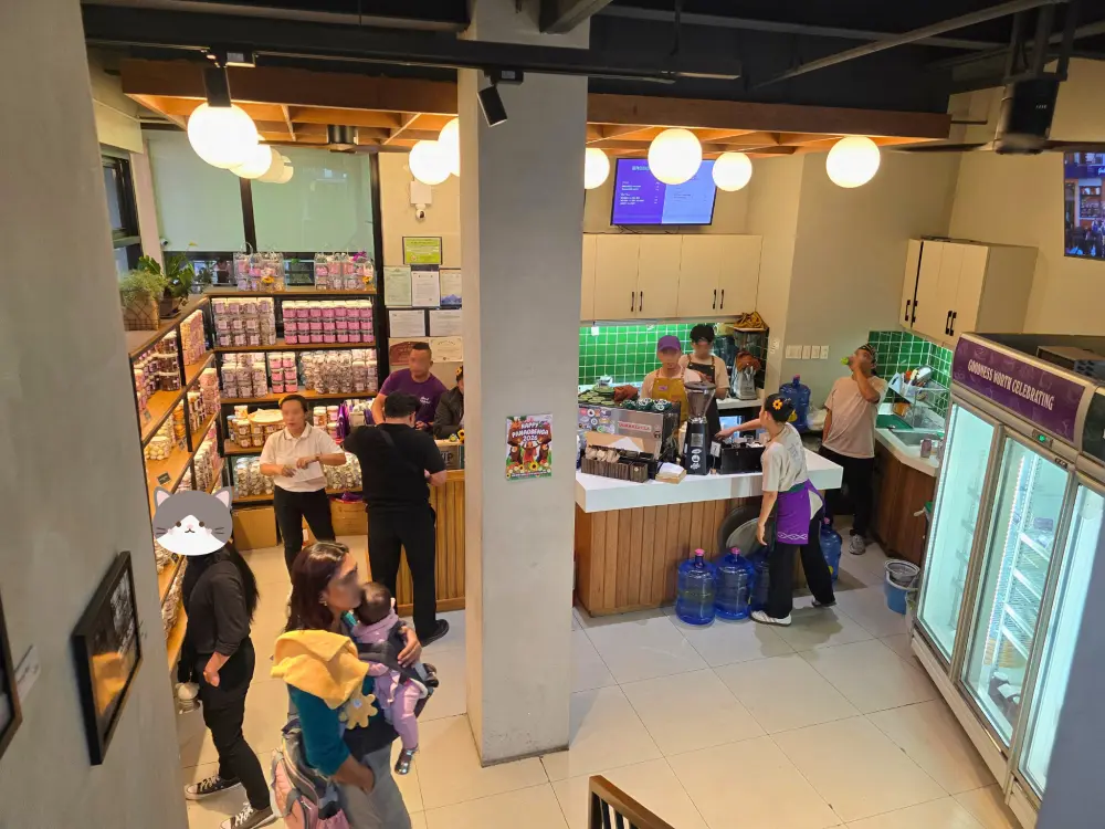 2階へ続く階段から見た、商品棚、カフェカウンター、冷蔵ショーケースがあるGood Shepherd Caféの1階
