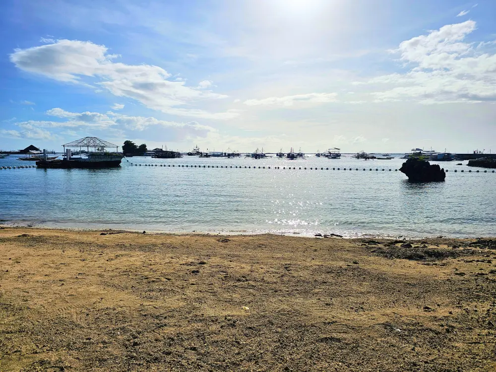 穏やかな海と沖に浮かぶバンカボートを望むEGIホテルの小さなビーチ