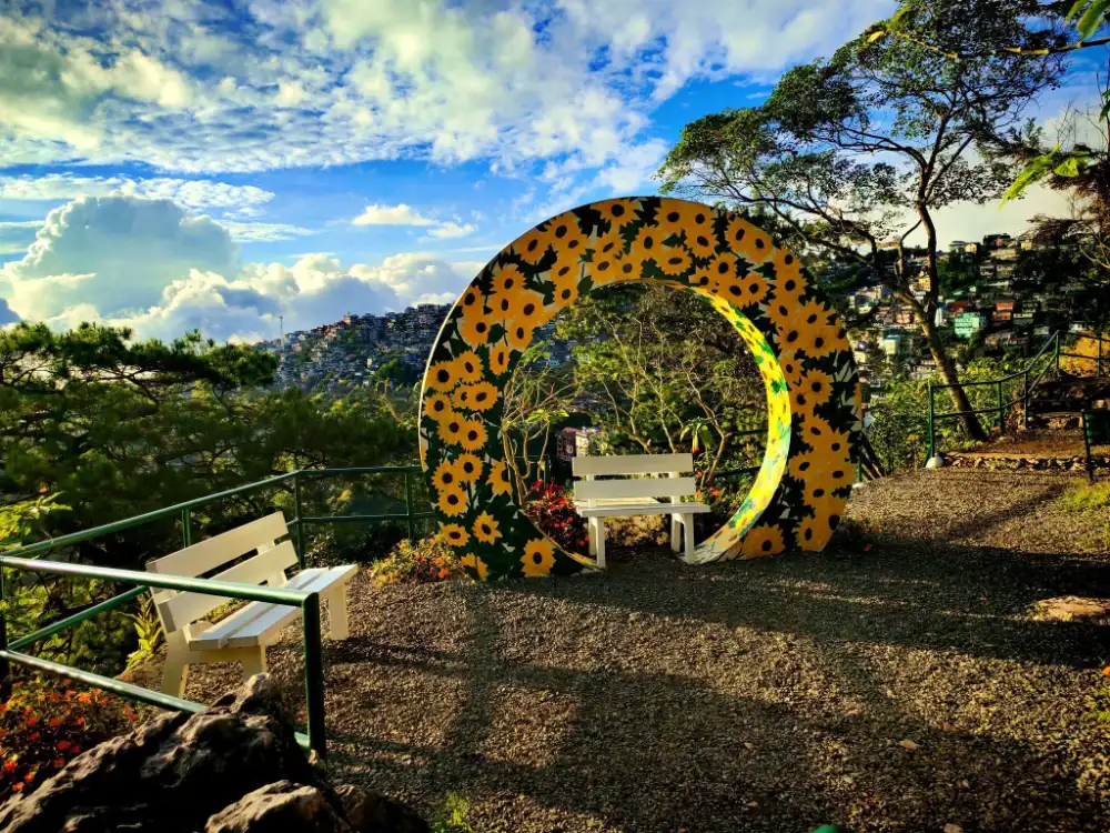 Mirador Heritage and Eco Parkのひまわり模様のアーチとBaguioの山並み