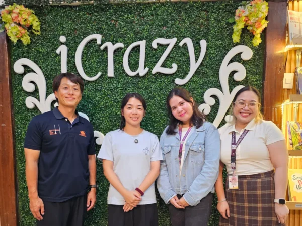 iCrazyのロゴ壁の前で並ぶ、ICLのヘッドティーチャーの2人とGrit留学の2人