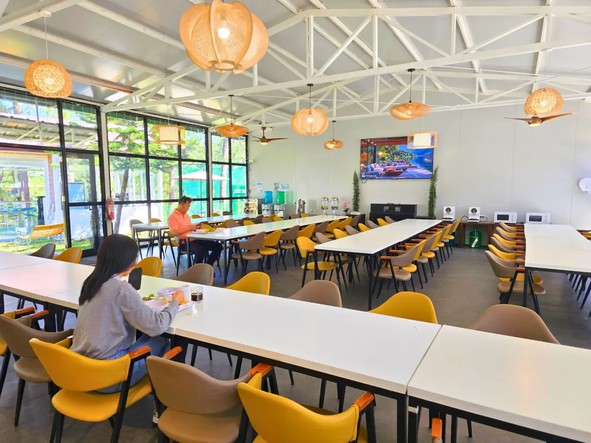 照明と大きな窓が印象的な、スタッフと学生がブランチを楽しむバギオのA&J ECO Campusの開放的なダイニングホール