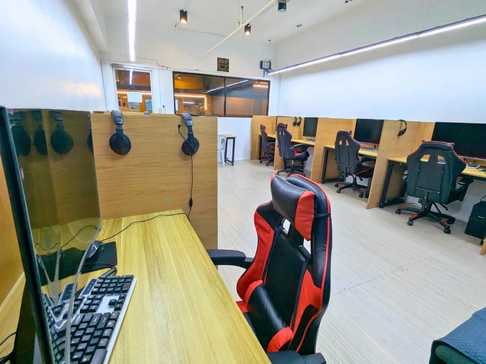 ICLのIELTS模擬テストルームに並ぶ、パーテーション付きPC席とヘッドセット、ゲーミングチェア