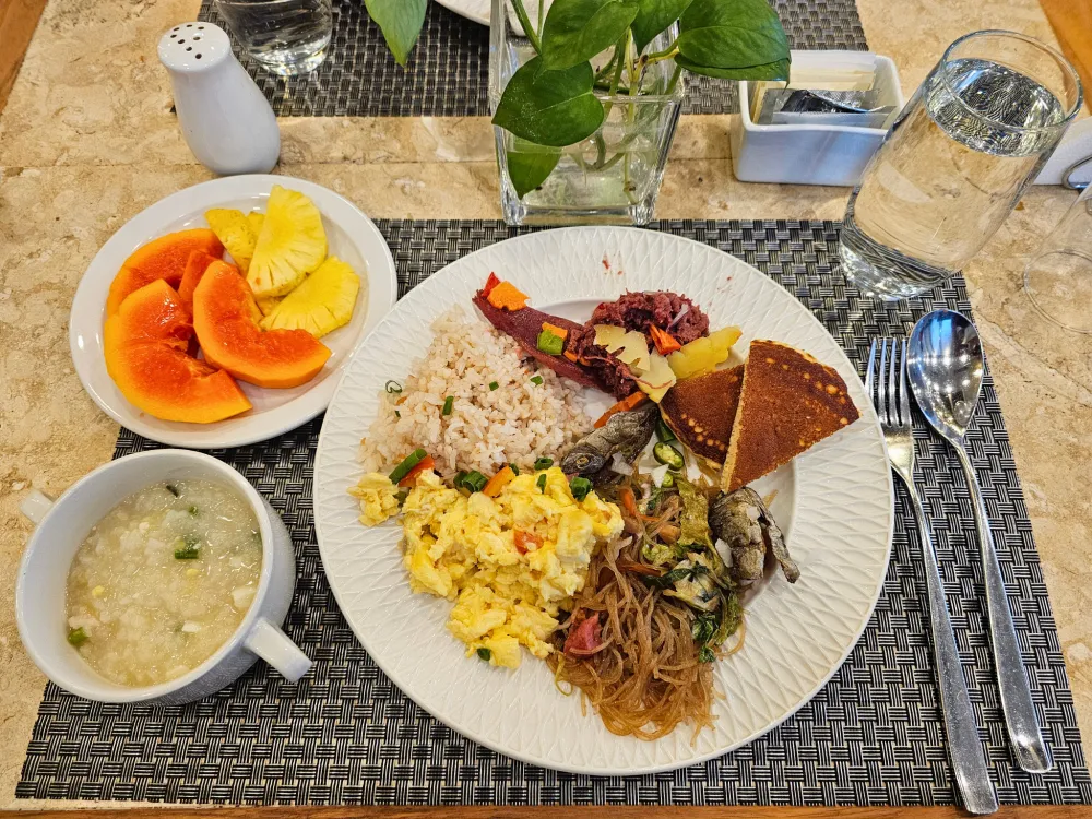 朝食として取り分けたフライドライス、パンケーキ、コーンビーフ、パンシット・ビーフン、スクランブルエッグ、ダンギット、パイナップル、パパイヤ、おかゆなど