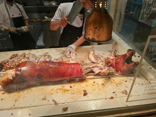 House of Lechonの店内で豚の丸焼きのレチョンを包丁で切り分ける調理スタッフ