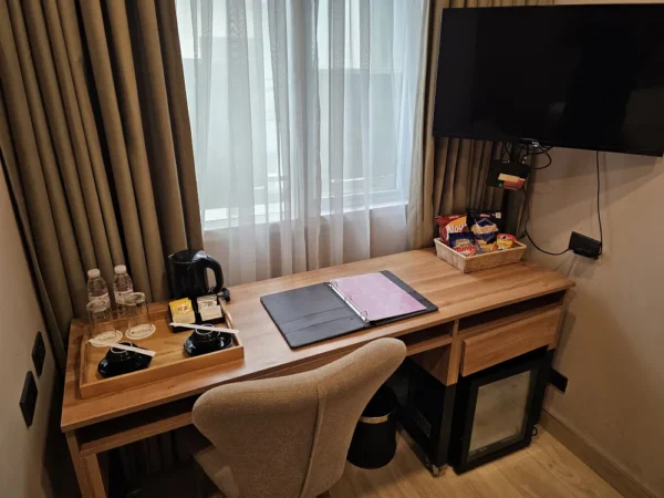 2本のペットボトル入り飲料水、コーヒーカップ、電気ケトル、案内ファイル、スナックが置かれたスタジオルームのデスク