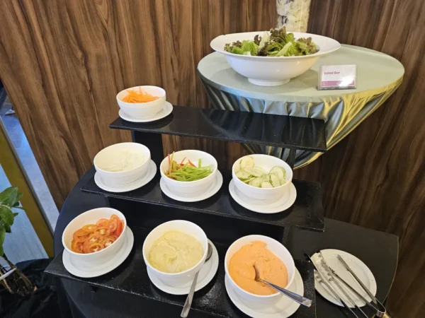 ビュッフェカウンターのサラダバーに並べられた、生野菜のにんじん、レタス、トマト、きゅうり、ピーマン、ドレッシング