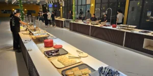 フィリピンのセブ・マクタン島にあるB'Cebuのダイニングで、パンや料理が並ぶブッフェカウンターから食事を選ぶ学生たち