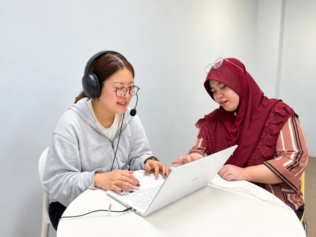 JIC Premium Campusで、ヘッドセットを着けてノートPCを操作する学生と、画面を確認する講師