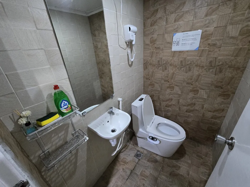 トリプルルームのトイレと洗面台、洗浄機能付き便座、大きな鏡、壁掛けヘアドライヤー、洗面用小物ラック