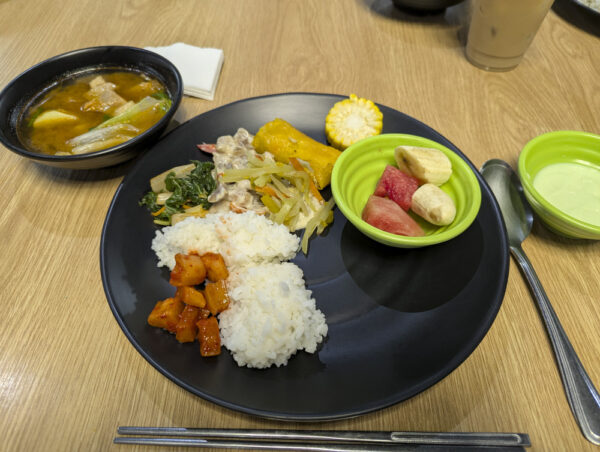 白ご飯と豚肉のクリーム煮、ペッチャイやサヨーテの炒め物、野菜ルンピア、フルーツなどに、豚肉と野菜のスープとパンダンヨーグルトを添えた昼食
