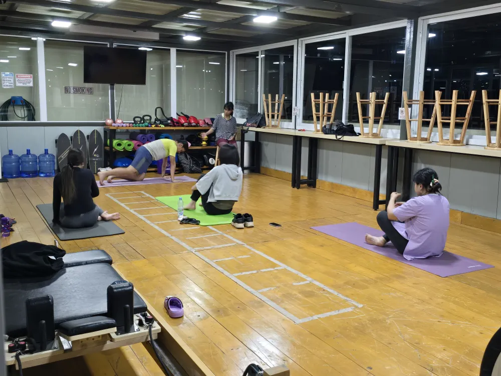 MONOL Main Campusのジムで行われるヨガクラス、3人の学生とポーズを実演するアシスタント、指導するプロのヨガインストラクター