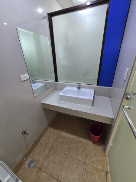 壁掛け鏡と洗面台、ゴミ箱が設置された1人部屋Ｃ用トイレの洗面スペース