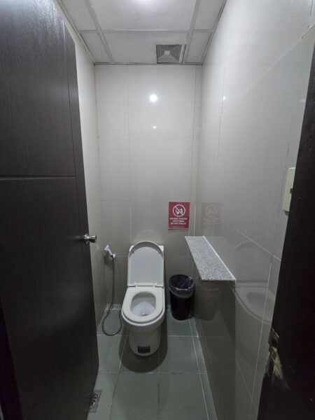 洋式トイレとハンドビデ、ゴミ箱、小物棚が設置された4人部屋Type2の独立したトイレ