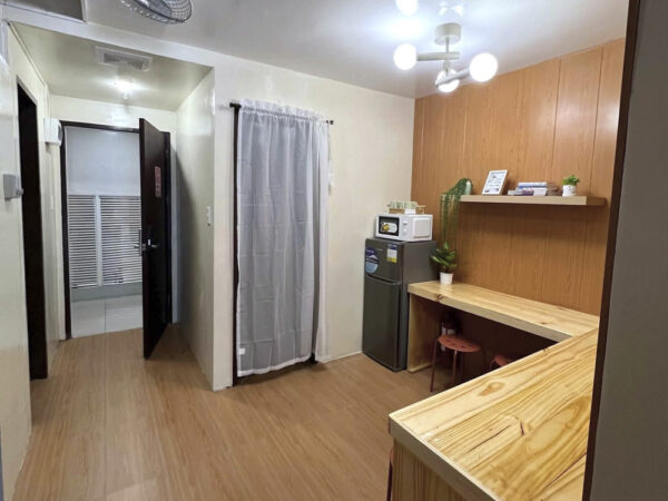 冷蔵庫と電子レンジ、木製カウンター、スツールが配置された5人部屋Soloの共用エリア