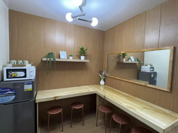L字型の木製カウンターと5脚のスツール、大きな壁掛け鏡が設置された5人部屋Soloの共用エリア