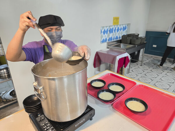 夕食時のビュッフェカウンターで、クラムチャウダーを器に注ぐPinesのキッチンスタッフ