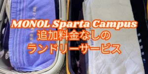 フィリピンのバギオにあるMONOL Sparta Campusのランドリーサービスで、洗濯後にたたまれた紫色と白色のタオルが2つのバスケットに収められた写真に、MONOL Sparta Campus 追加料金なしのランドリーサービスの文字を重ねた画像